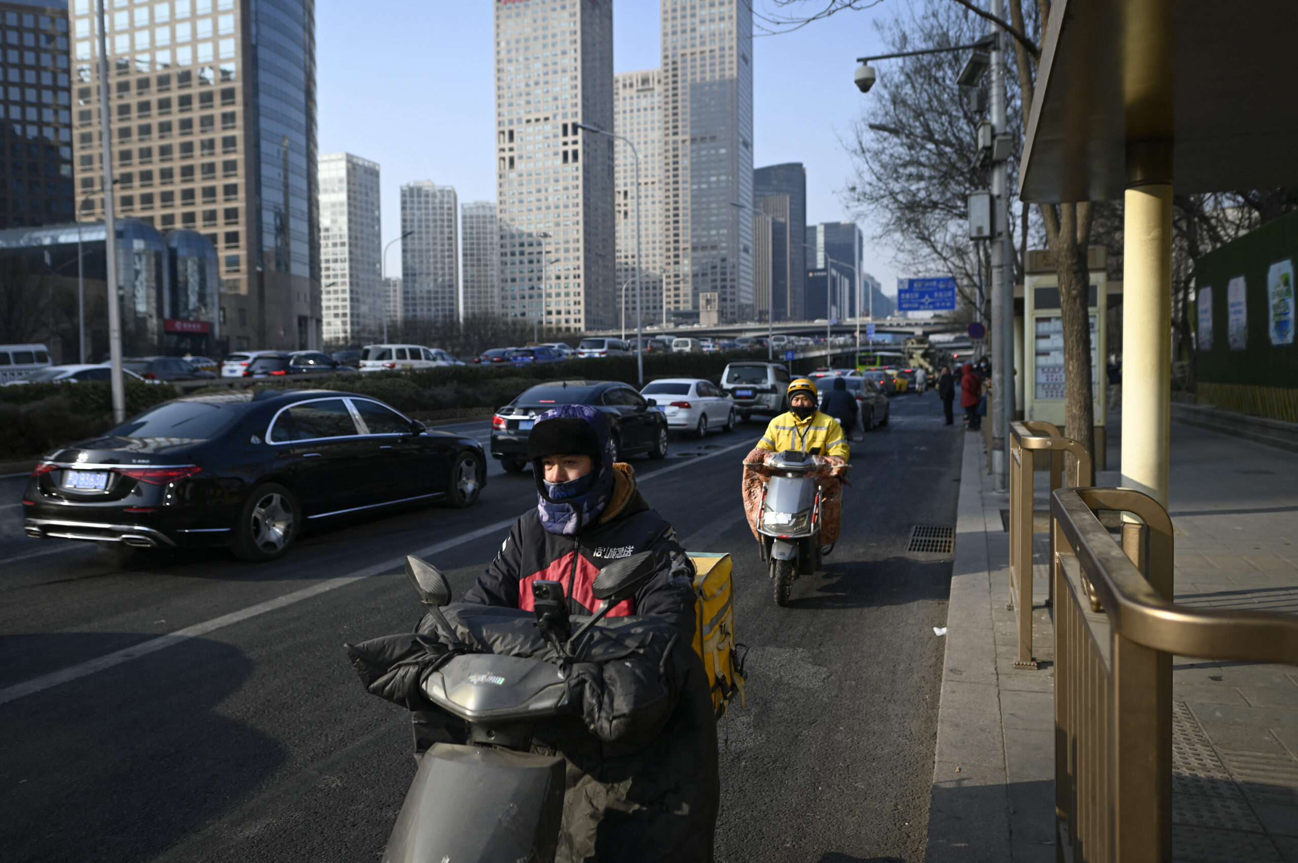 Food delivery men ride electric scooters along a street at Central Business District (CBD) in Beijing on January 16, 2024.